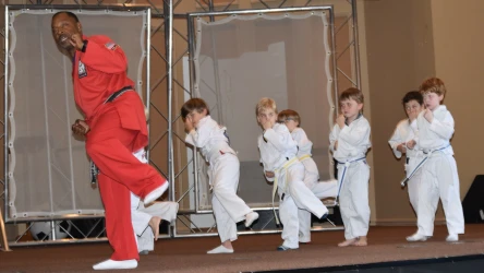 a person in a red suit and white pants with a group of children doing karate