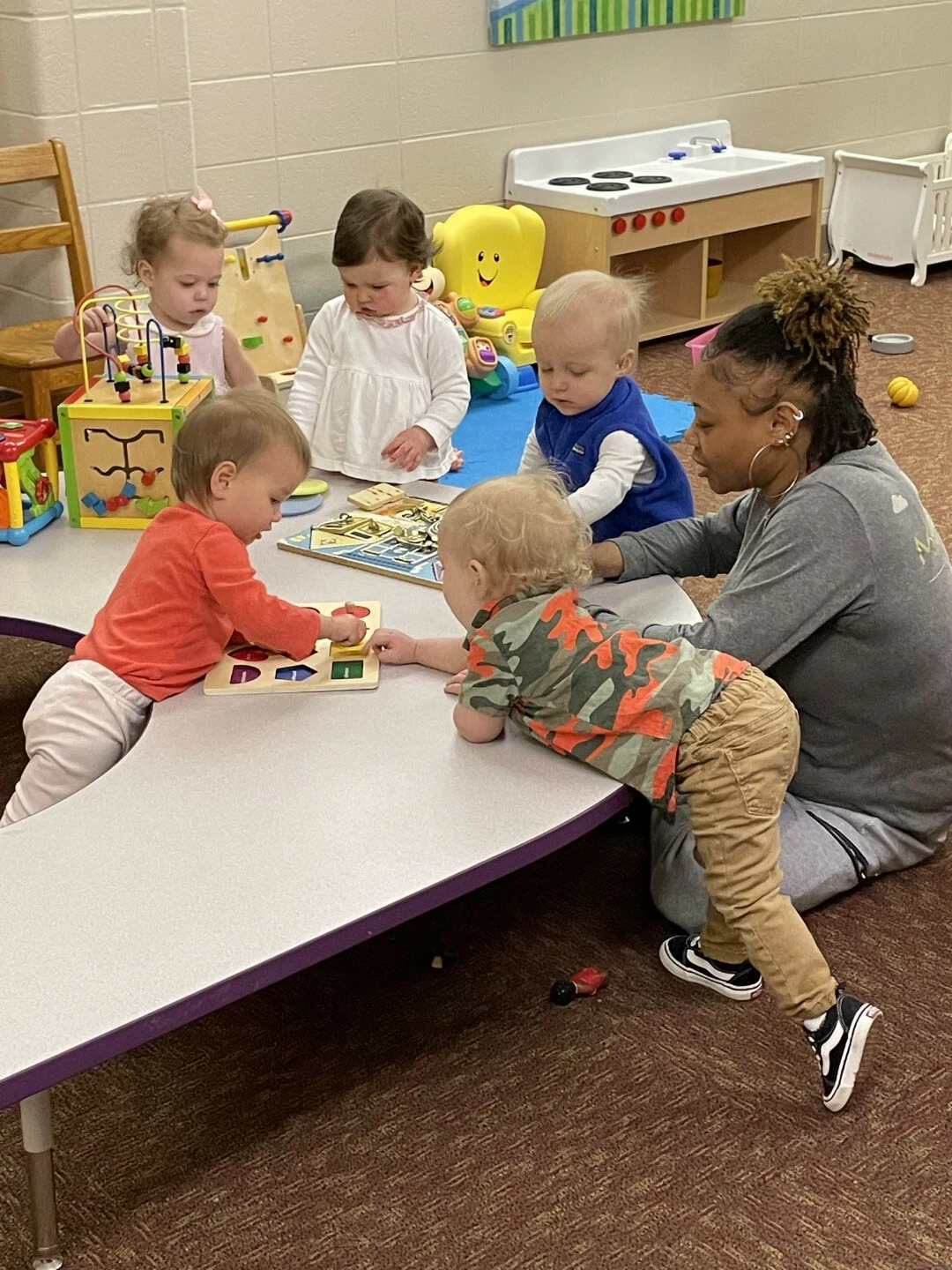 a person and several children playing with toys on a table